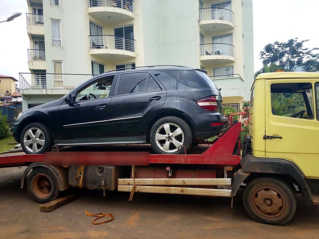 Mercedes ML 4x4 chargé sur camion-plateau devant un immeuble à Yaoundé